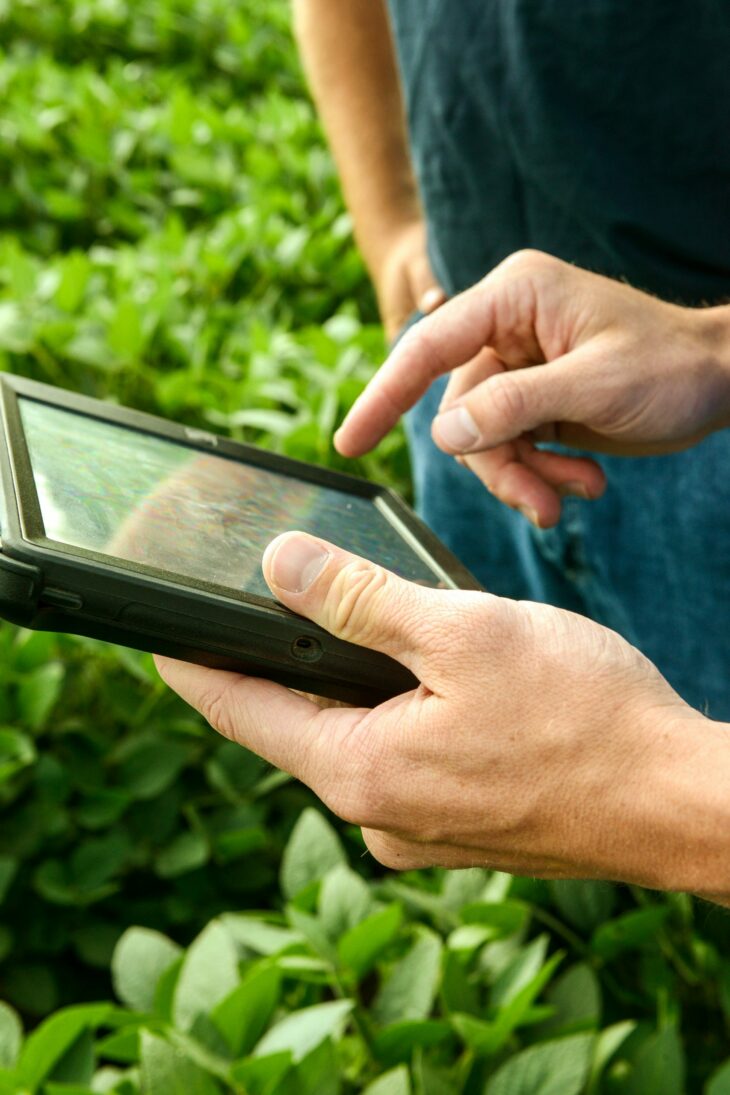 Hands pointing to a tablet showing precision ag software