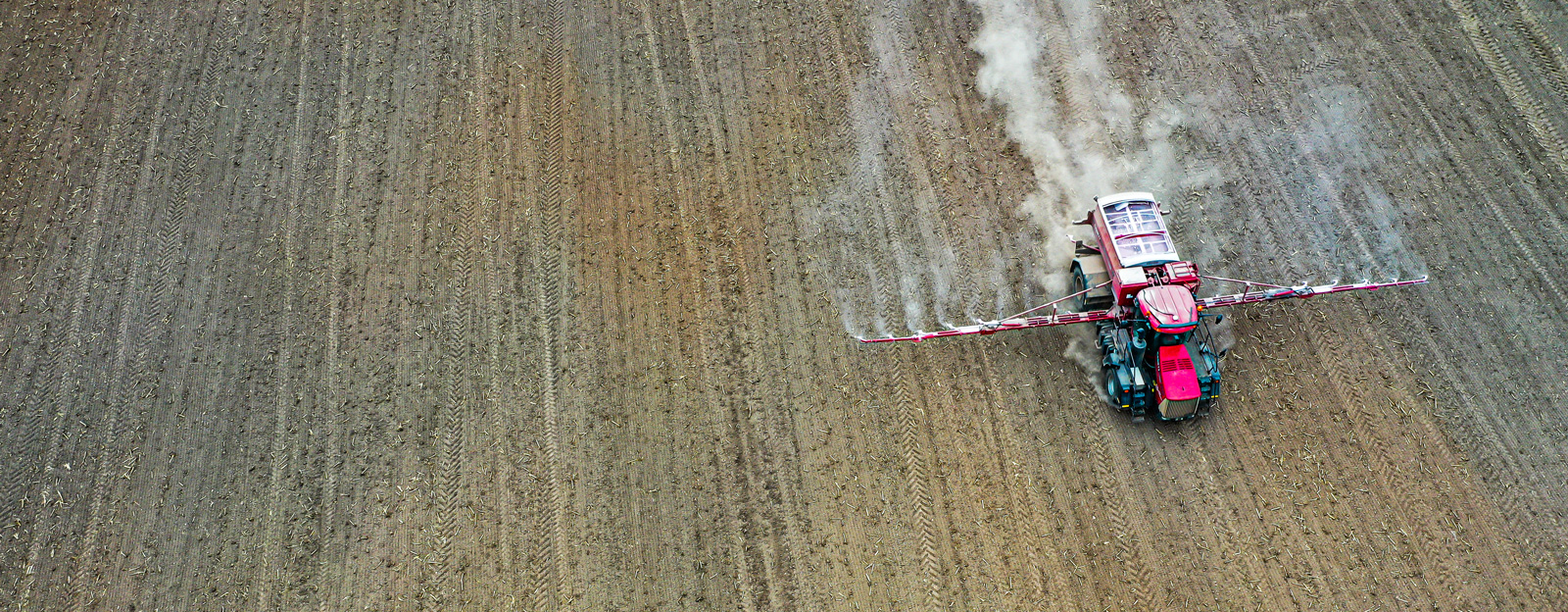 Tractor with sprayer attachments driving through a field