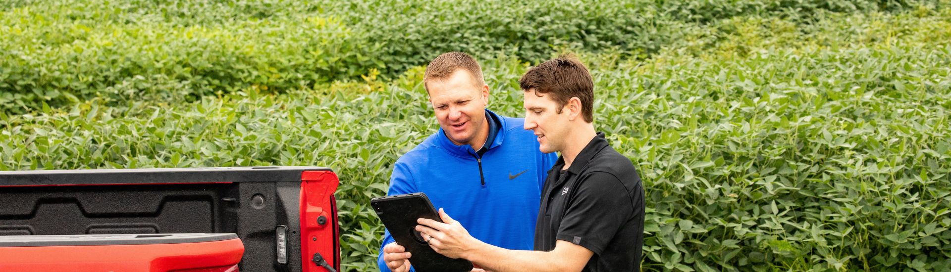 Two men standing by a truck on a tablet.